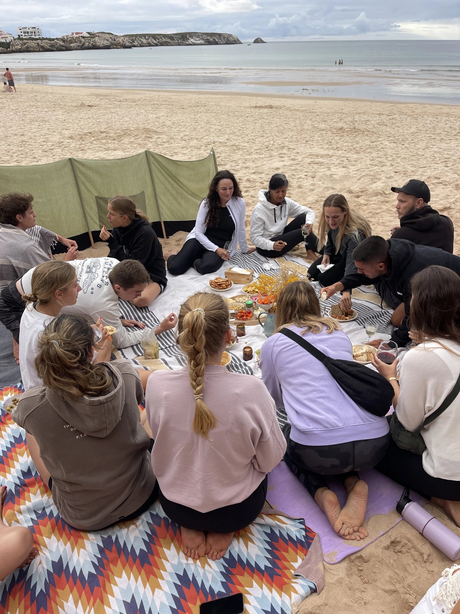 Group sharing a beach picnic after yoga in Baleal